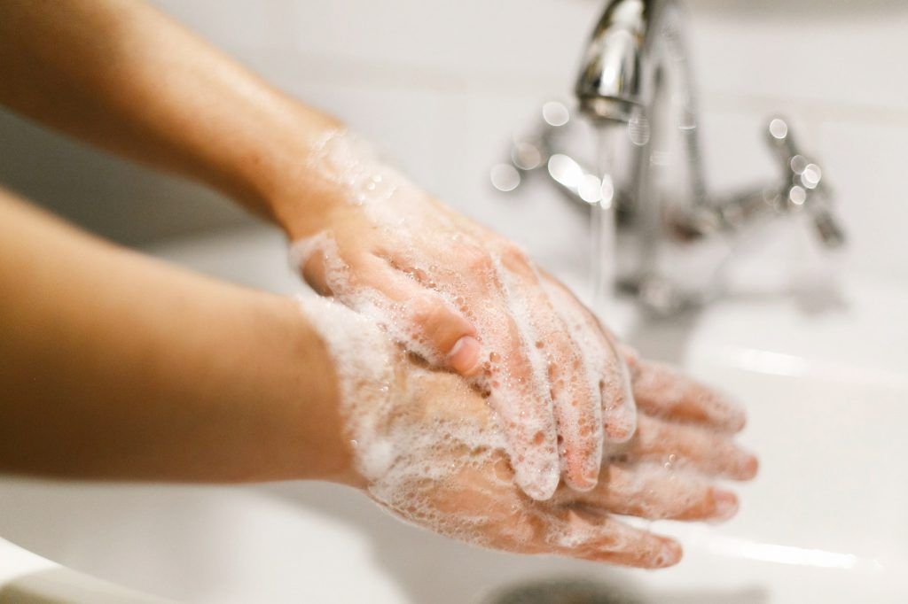 Hands washing with soap foam on background of flowing water