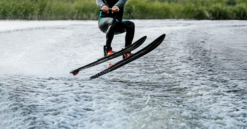 man waterskiing on lake behind boat