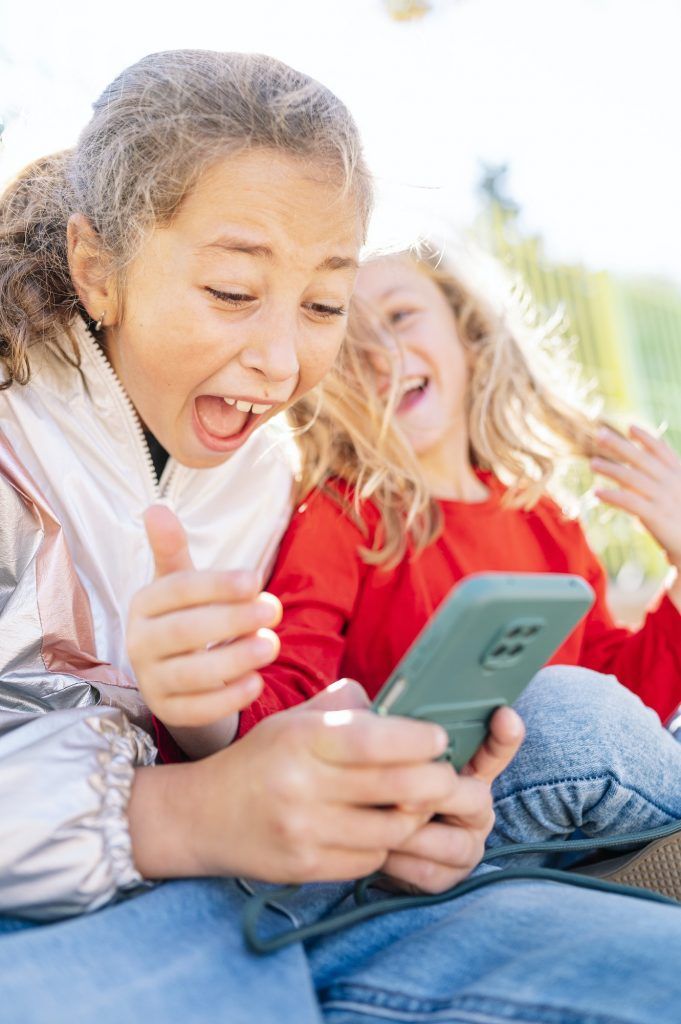 Two happy children. The girl holds a smartphone.