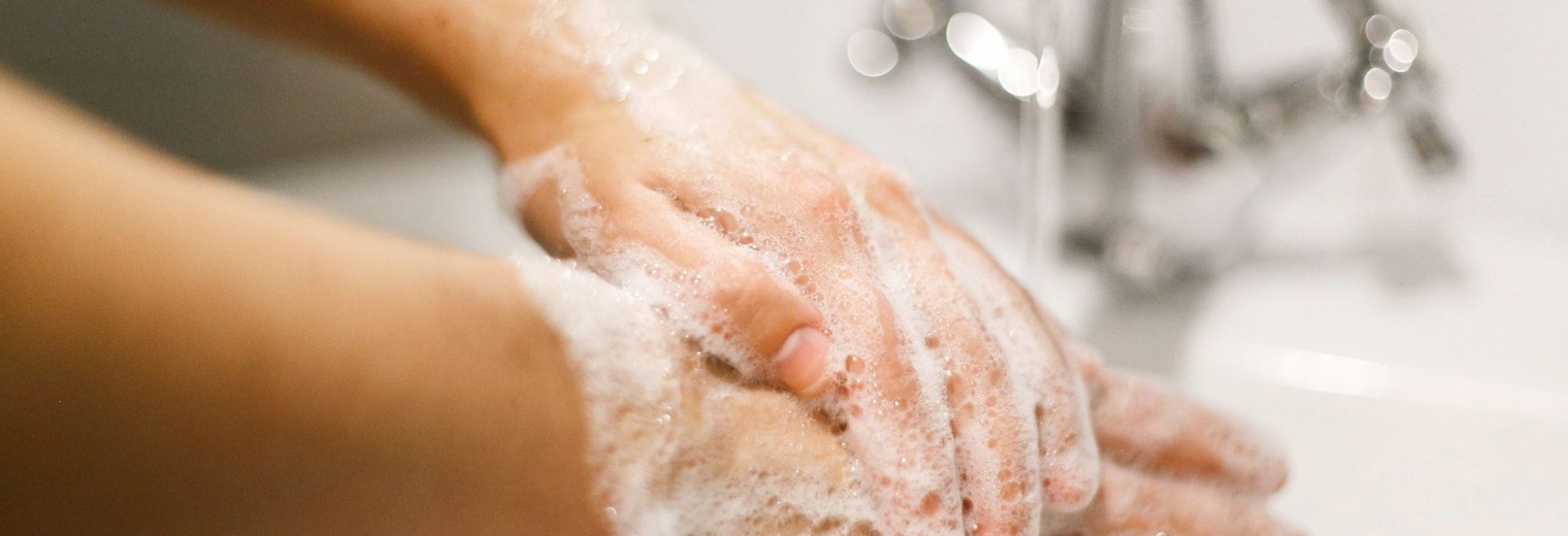 Hands washing with soap foam on background of flowing water